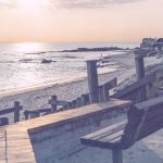 dreamy summer Sunset over a beach, with a bench and homes in the distance