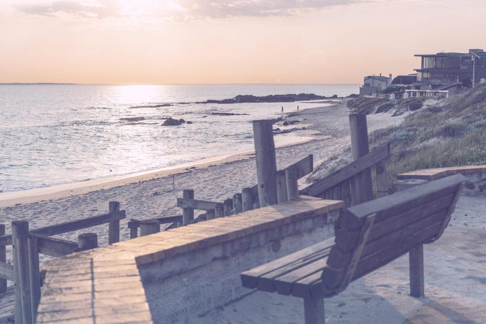 dreamy summer Sunset over a beach, with a bench and homes in the distance